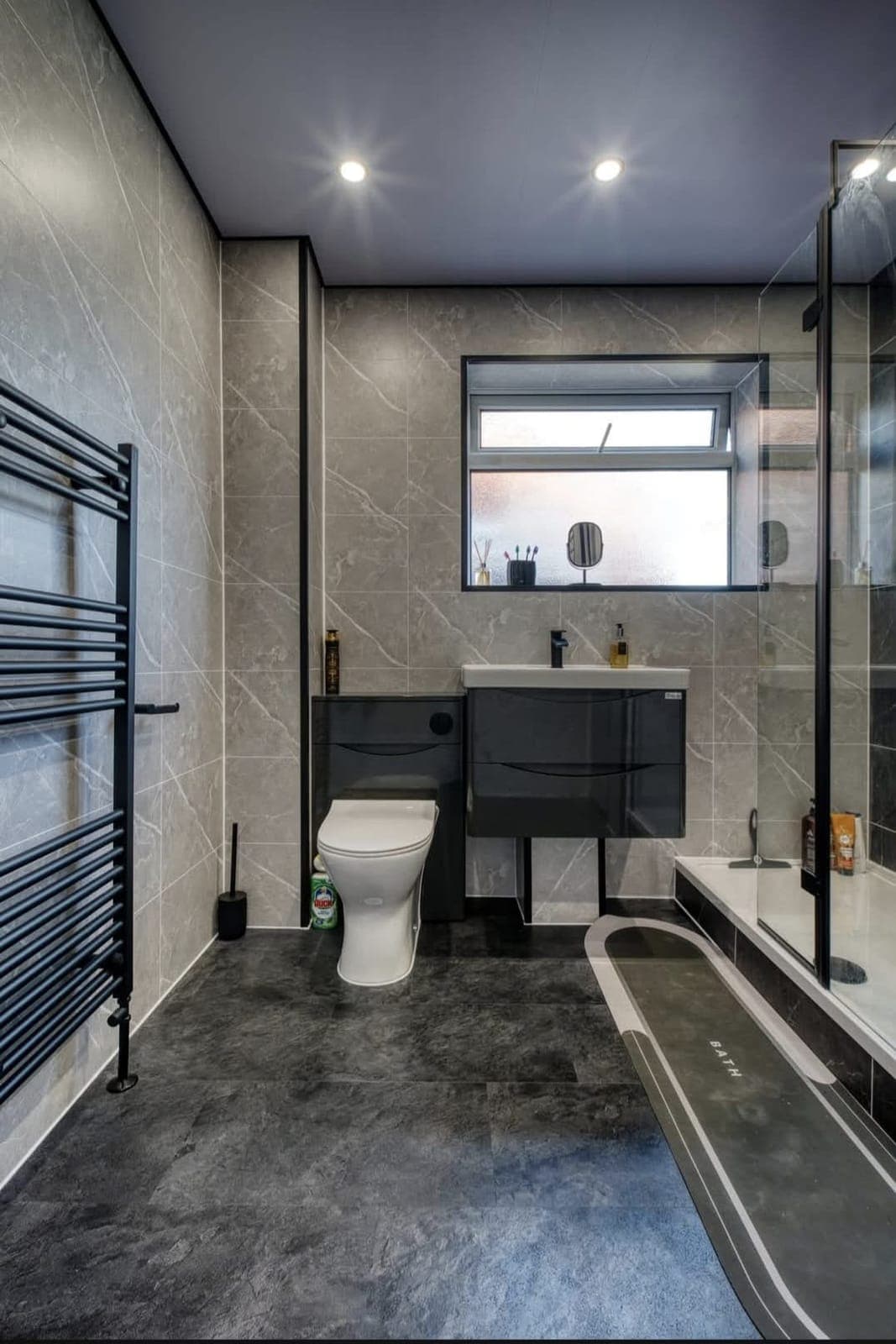 Modern bathroom with grey vanity unit, black heated towel rail and freestanding bath
