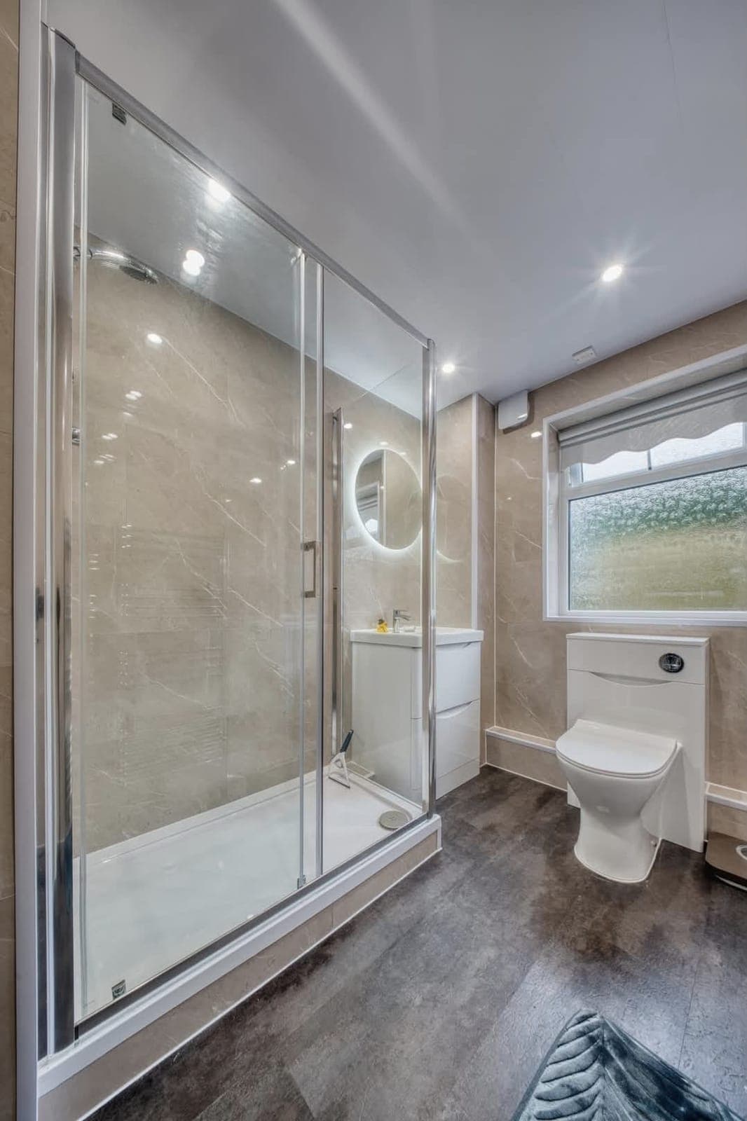 Frameless glass shower enclosure in a bathroom with wood-effect flooring