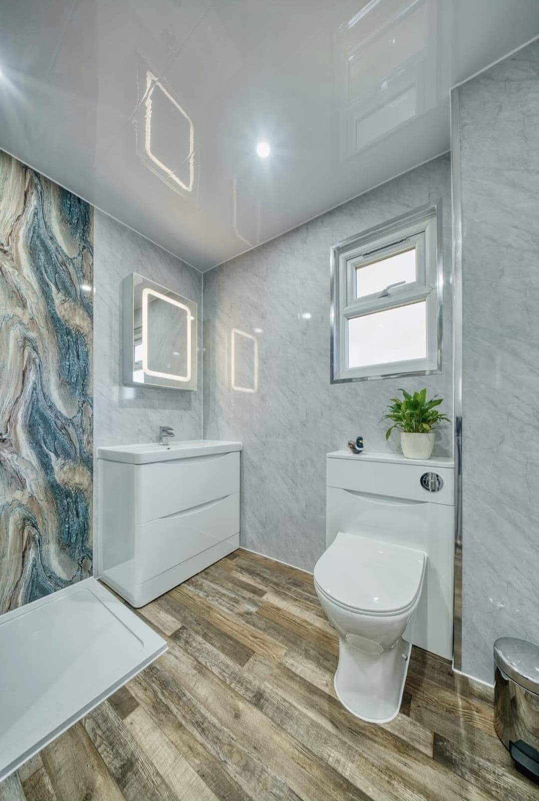 Bathroom with blue and gold marble feature panel, white vanity unit and wood-effect floor