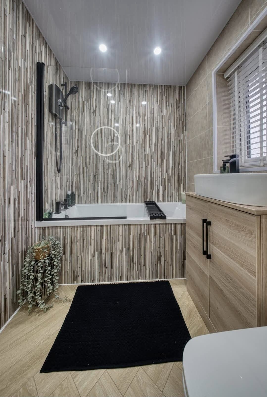 Bath and shower with wood-effect wall panelling and vanity unit on herringbone flooring