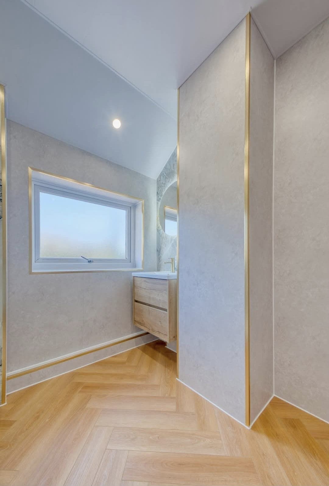 Bright bathroom with herringbone flooring, shower enclosure and gold trim detail