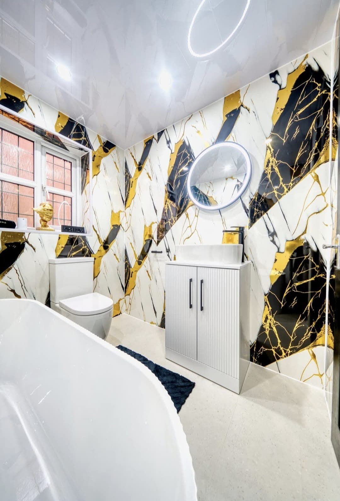 Bathroom with black, white and gold marble feature walls and a freestanding bath