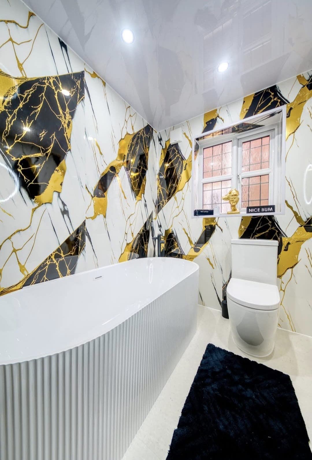 Freestanding fluted bath against black and gold marble wall panels