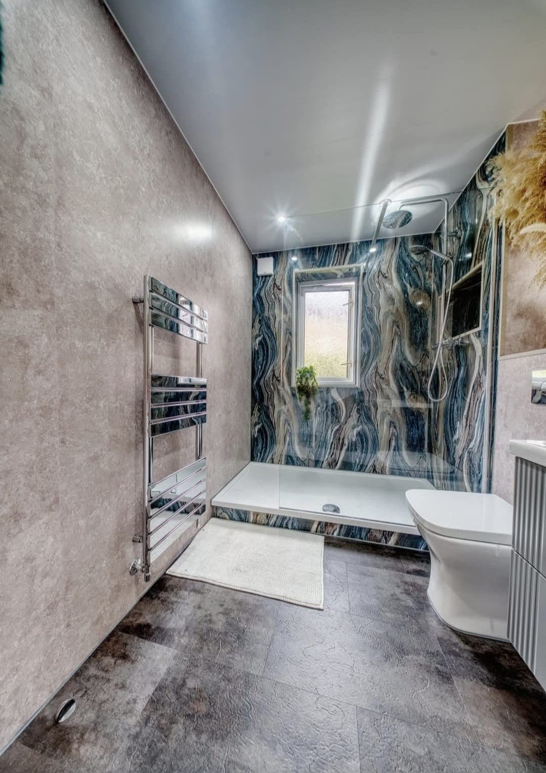 Bathroom with blue marble accent wall, chrome towel rail and walk-in shower