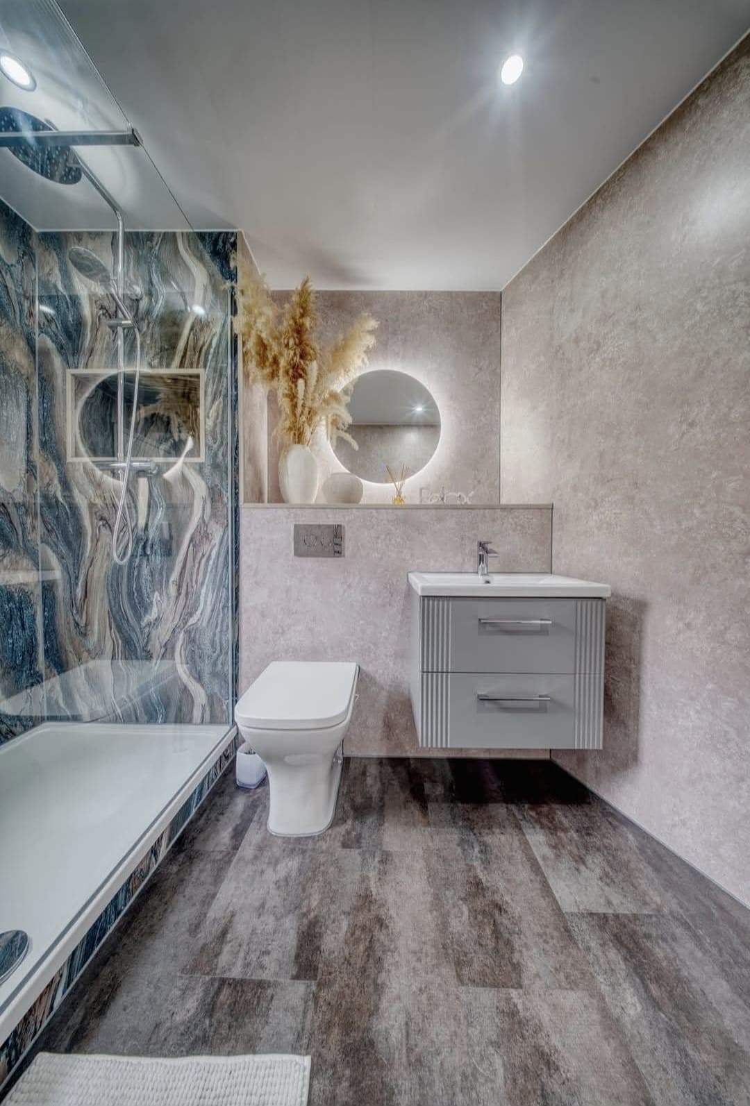 Walk-in shower with blue marble panel and wall-hung vanity beside a window