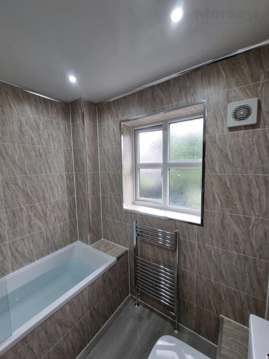 Compact bathroom with bath, chrome towel radiator and frosted window