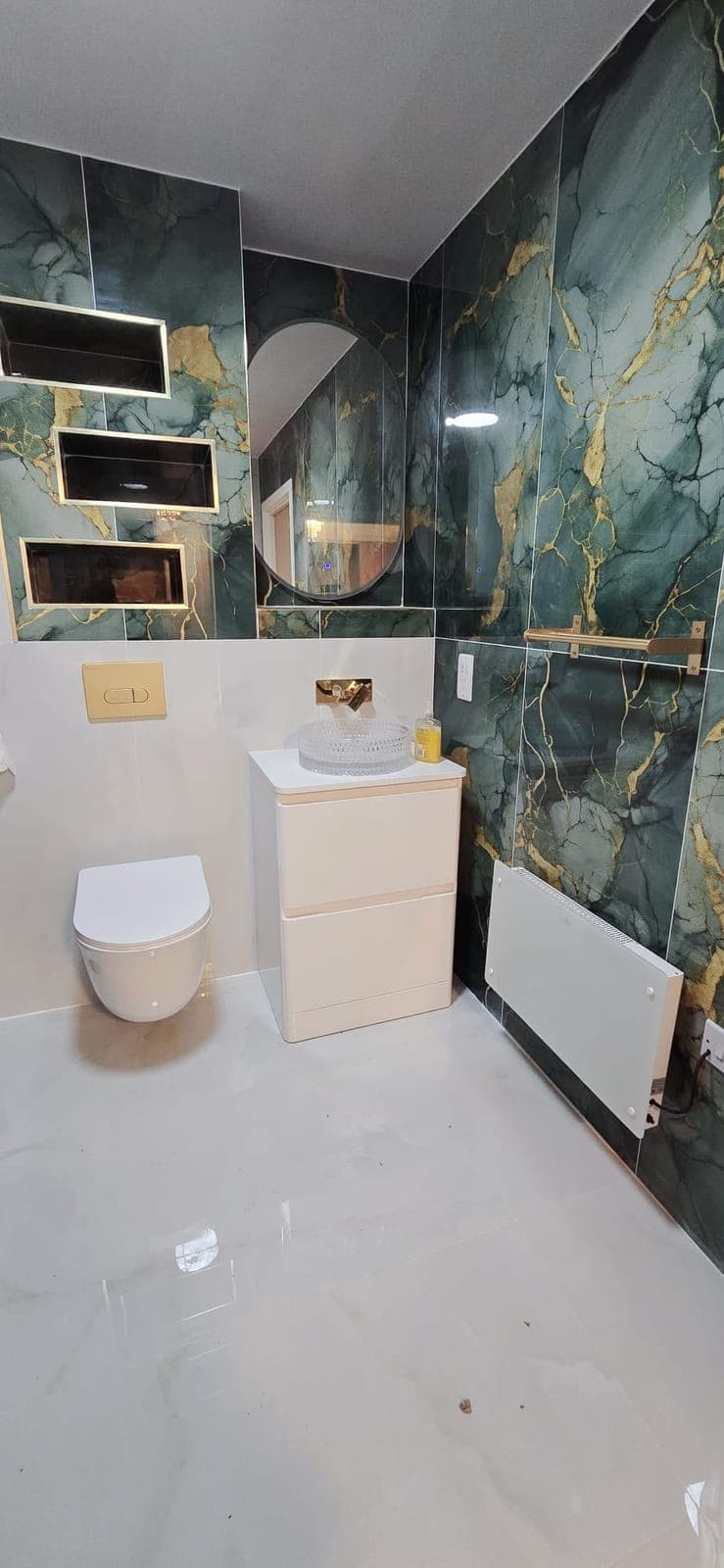 Bathroom with green marble feature wall and gold-veined shelving niches