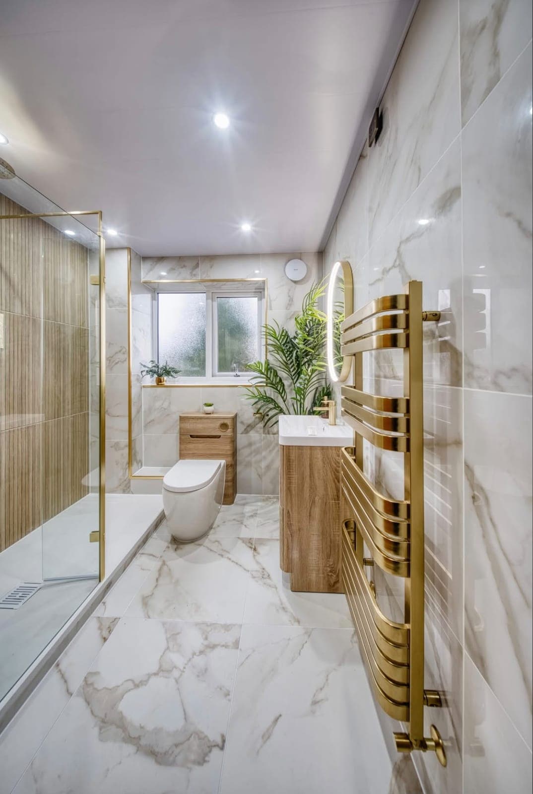 Marble-effect bathroom with walk-in shower, gold towel rail and oak vanity