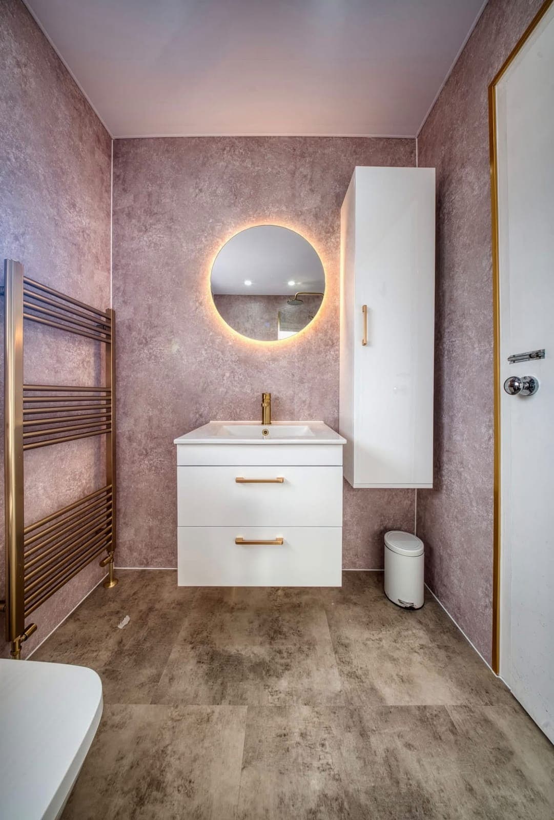 Bathroom with round backlit mirror, wall-hung vanity and tall storage cabinet