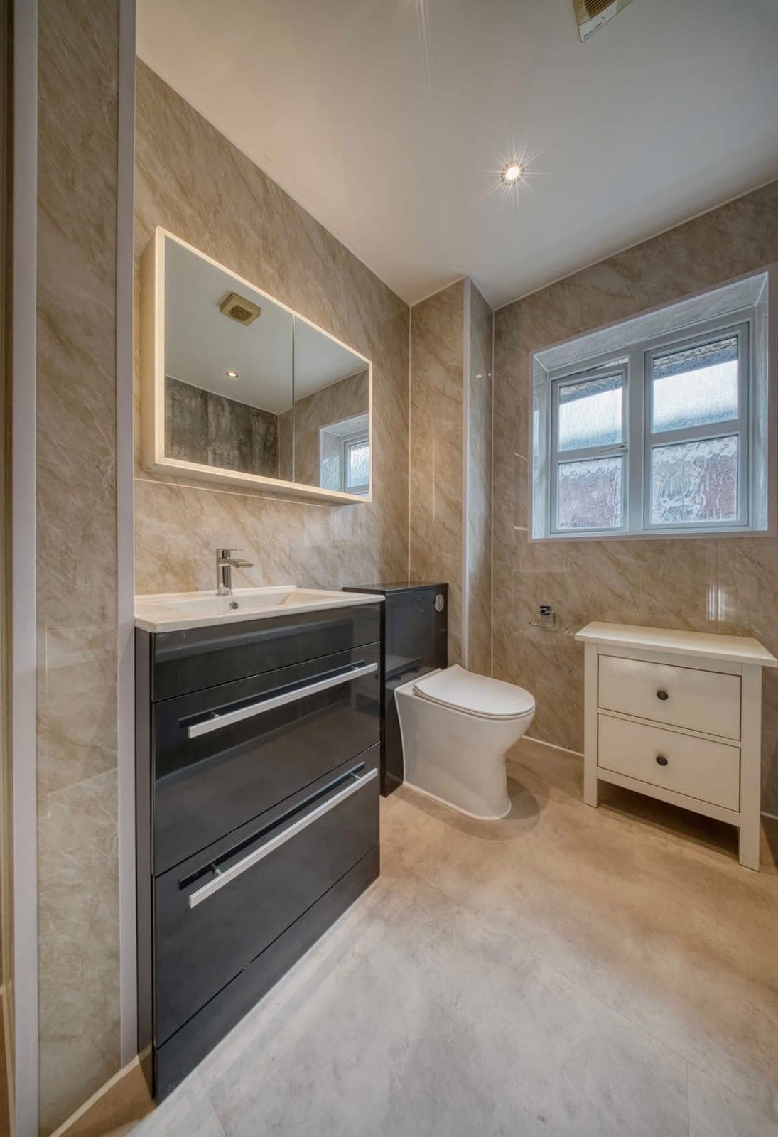 Bathroom with black vanity drawers, wall mirror and freestanding oak cabinet