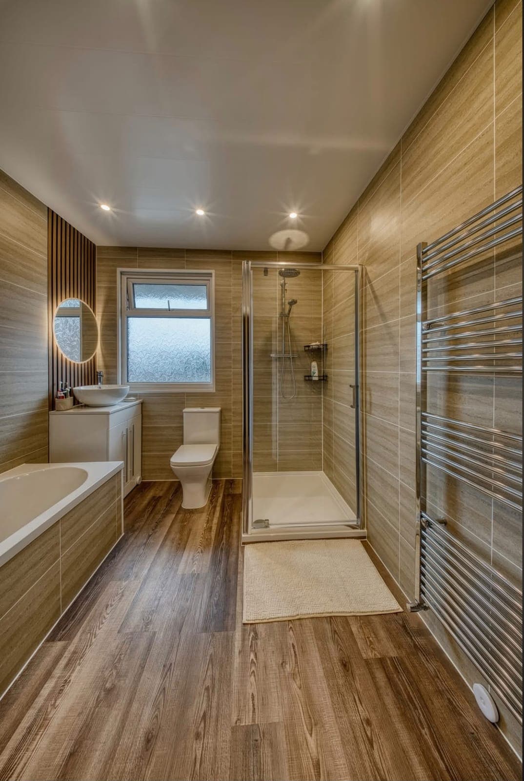 Wood-effect bathroom with glass shower enclosure, bath and chrome towel radiator