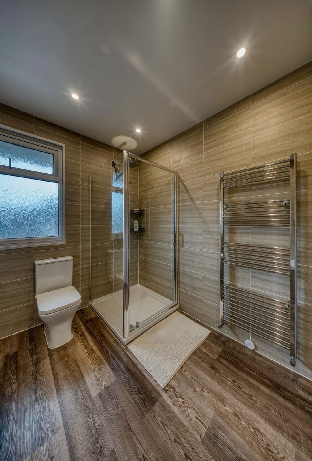 Bathroom with timber-look tiles, glass shower and chrome radiator