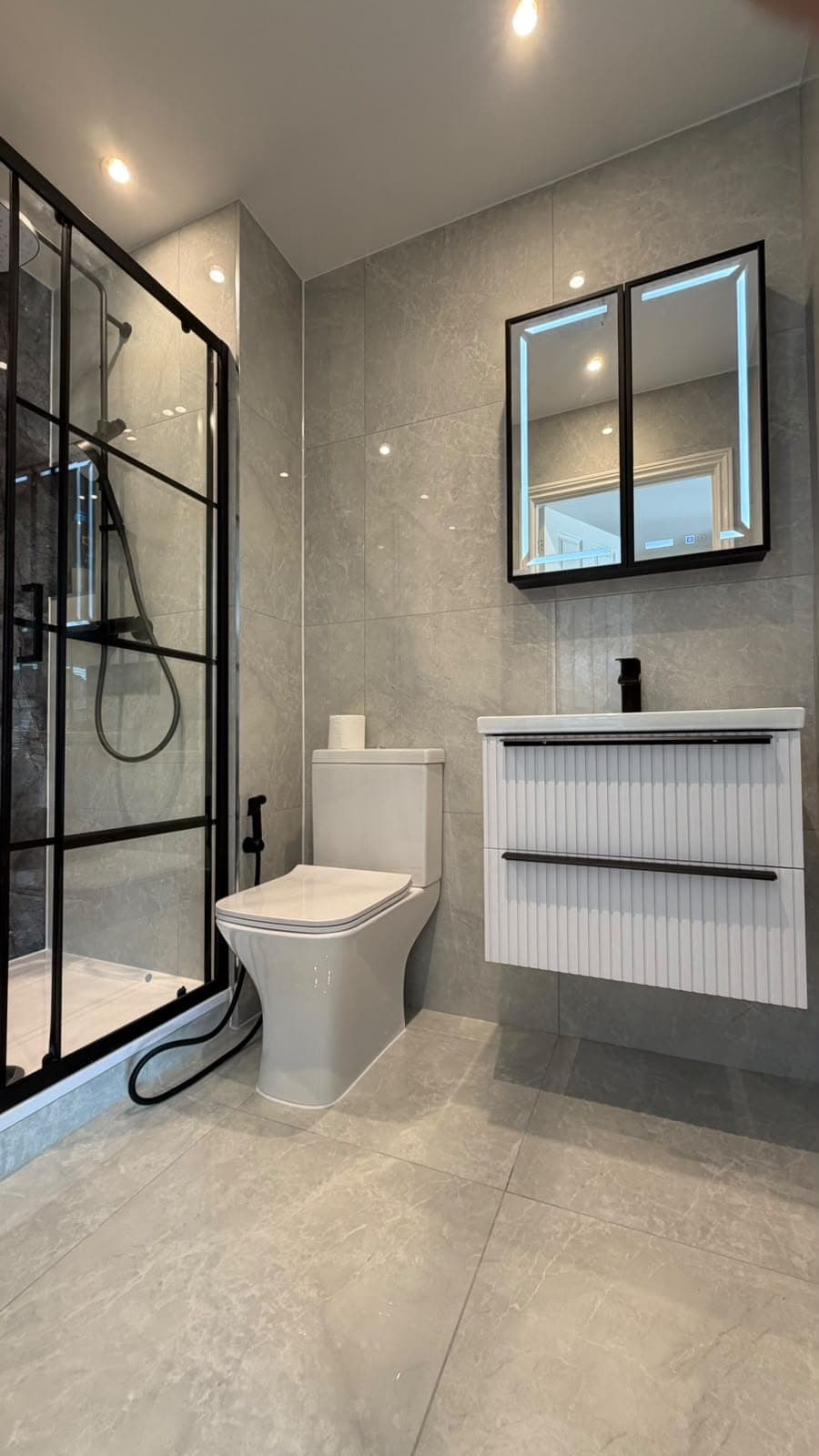 Black-framed walk-in shower, fluted vanity unit and mirror cabinet