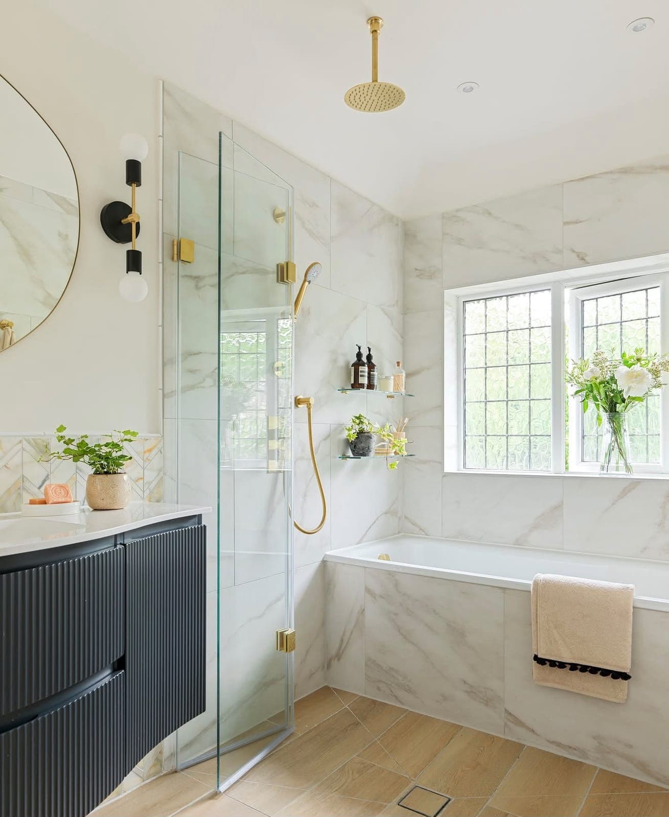 Bright marble-tiled bathroom with glass walk-in shower, bath and brass fittings